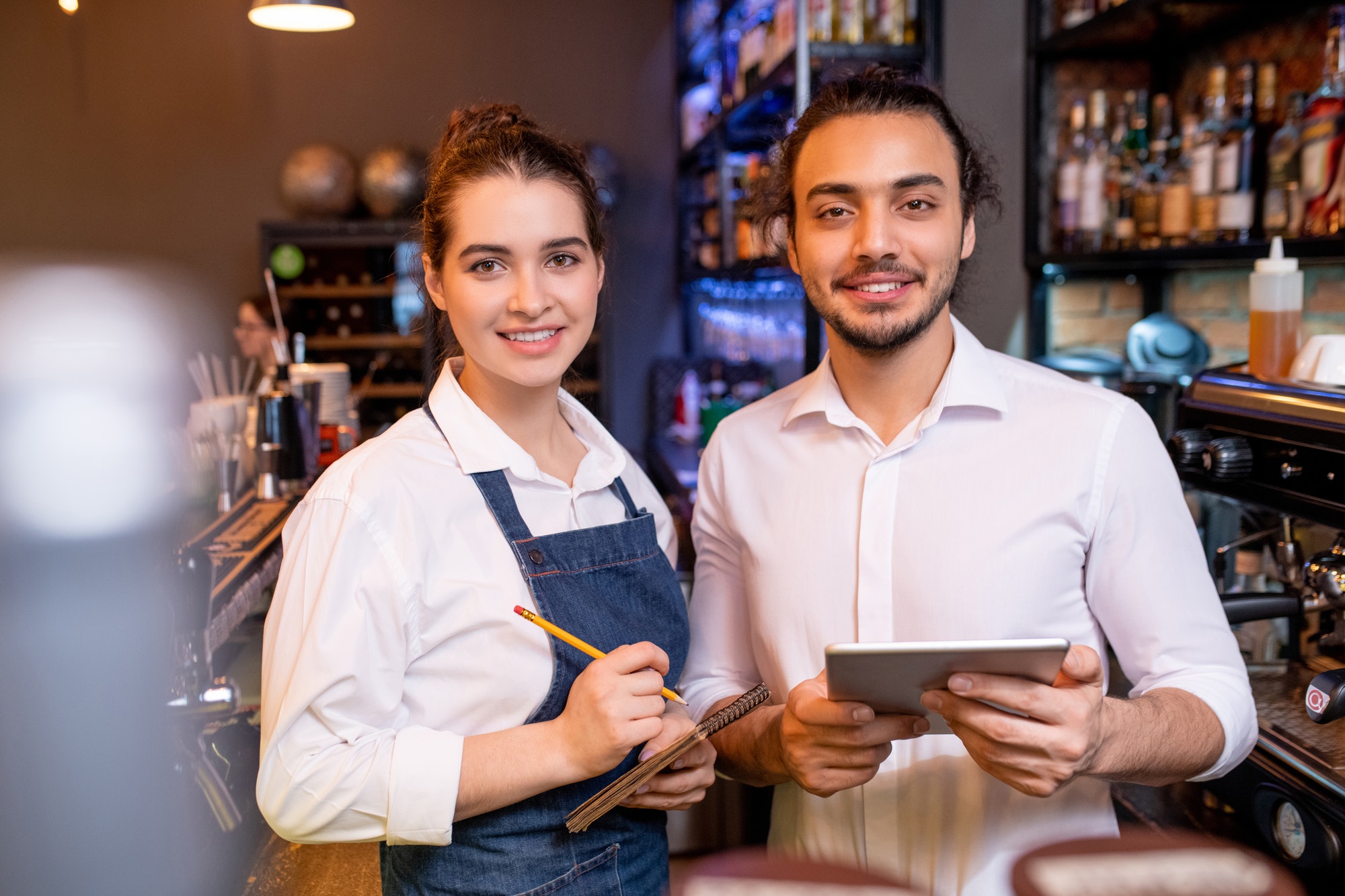 Dos jóvenes trabajadores alegres de los invitados de la reunión del restaurante o de la cafetería con clase