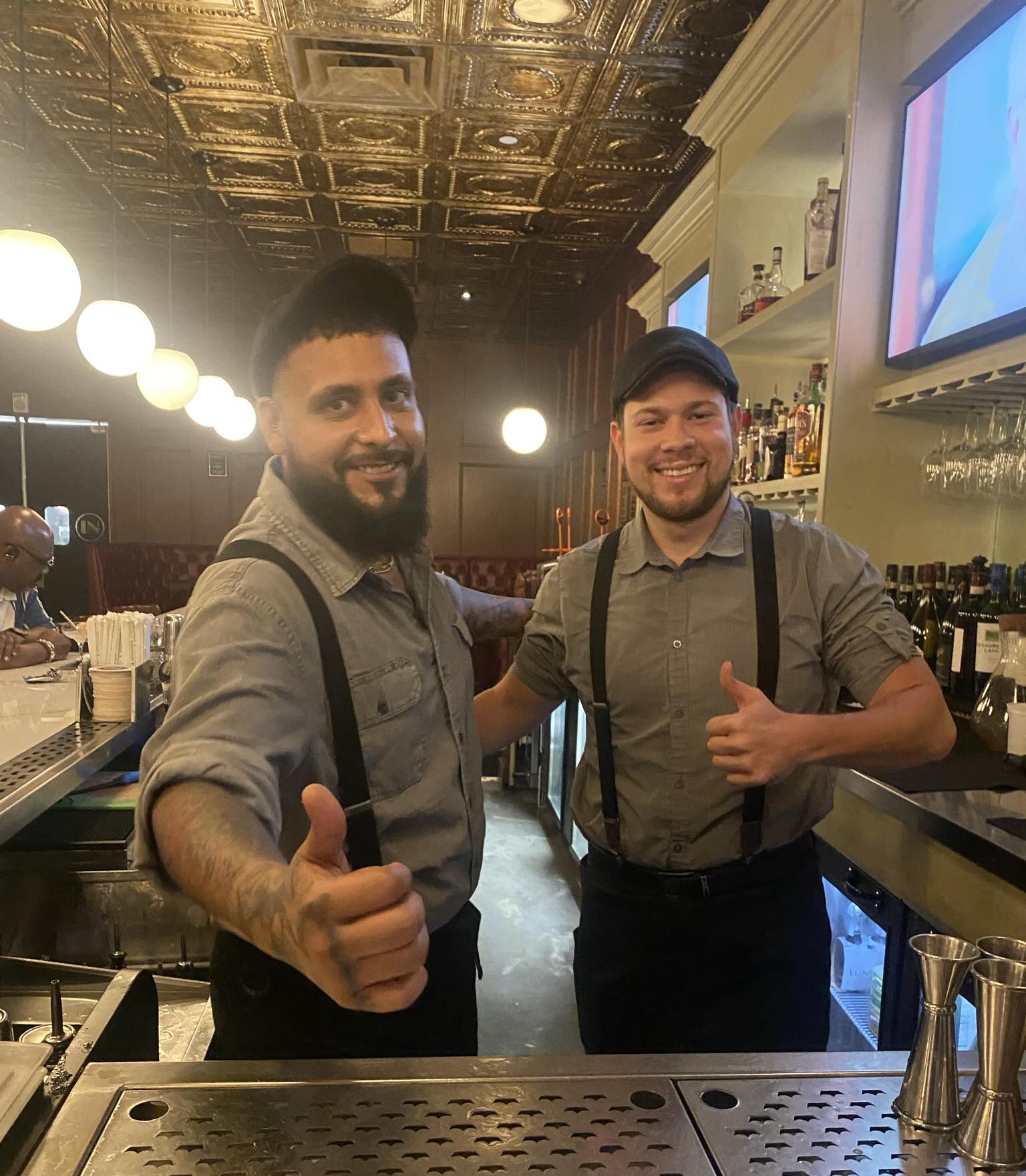 "AJ y Sam, de camarero en Divieto en Aventura, FL, mostrando sus habilidades mientras crean cócteles en un ambiente de bar vibrante."